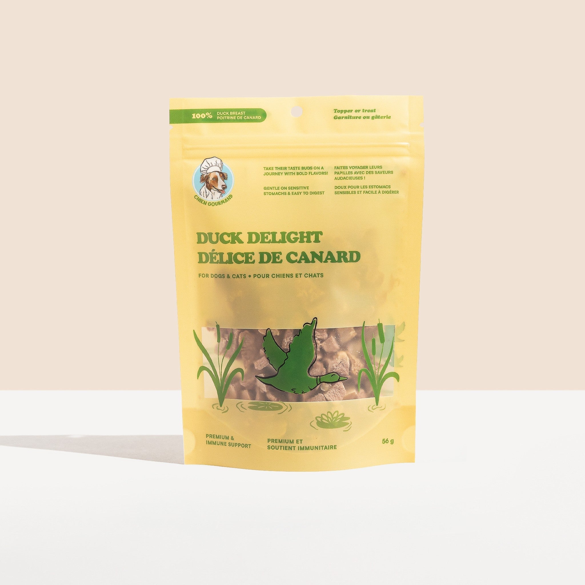 A full studio shot of the Chien Gourmand Duck Delight 56g stand-up pouch, showcasing the light yellow package design with a green flying duck illustration over a clear product window.