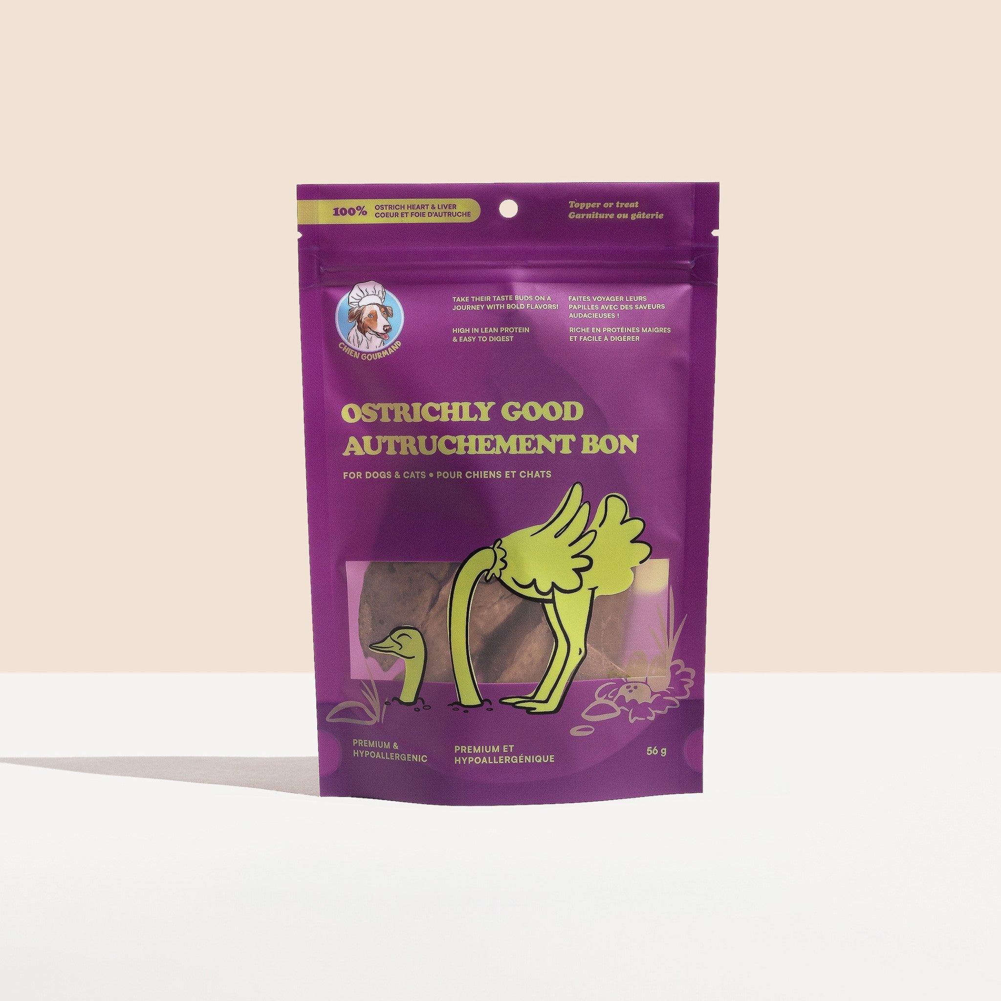 A front-facing studio shot of a 56g purple stand-up pouch of Chien Gourmand Ostrichly Good dog treats, featuring a fun ostrich illustration and bilingual English/French product labeling.