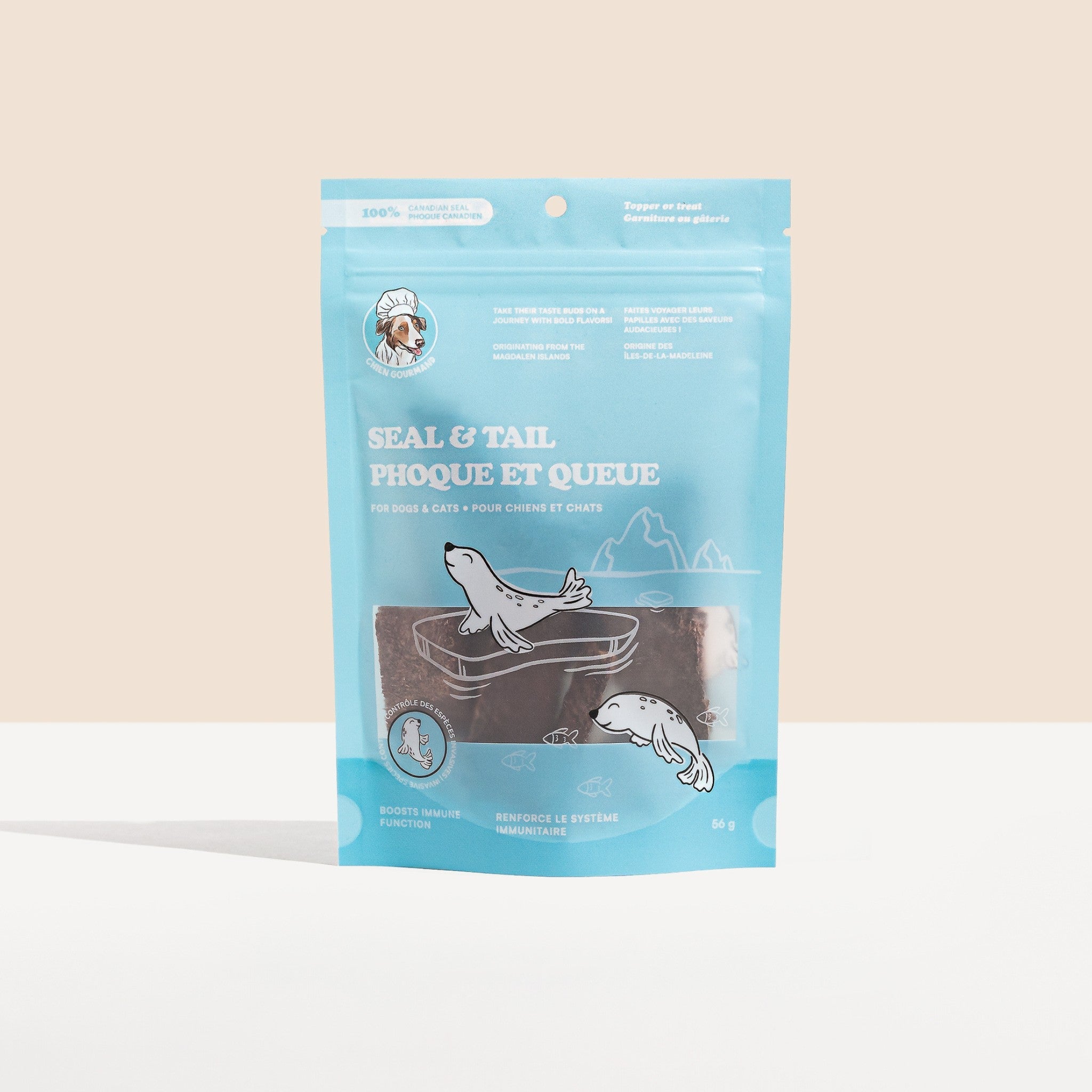 A top-down lifestyle view showing freeze-dried seal meat pieces tumbling out from a light blue Chien Gourmand product pouch onto a clean white surface.