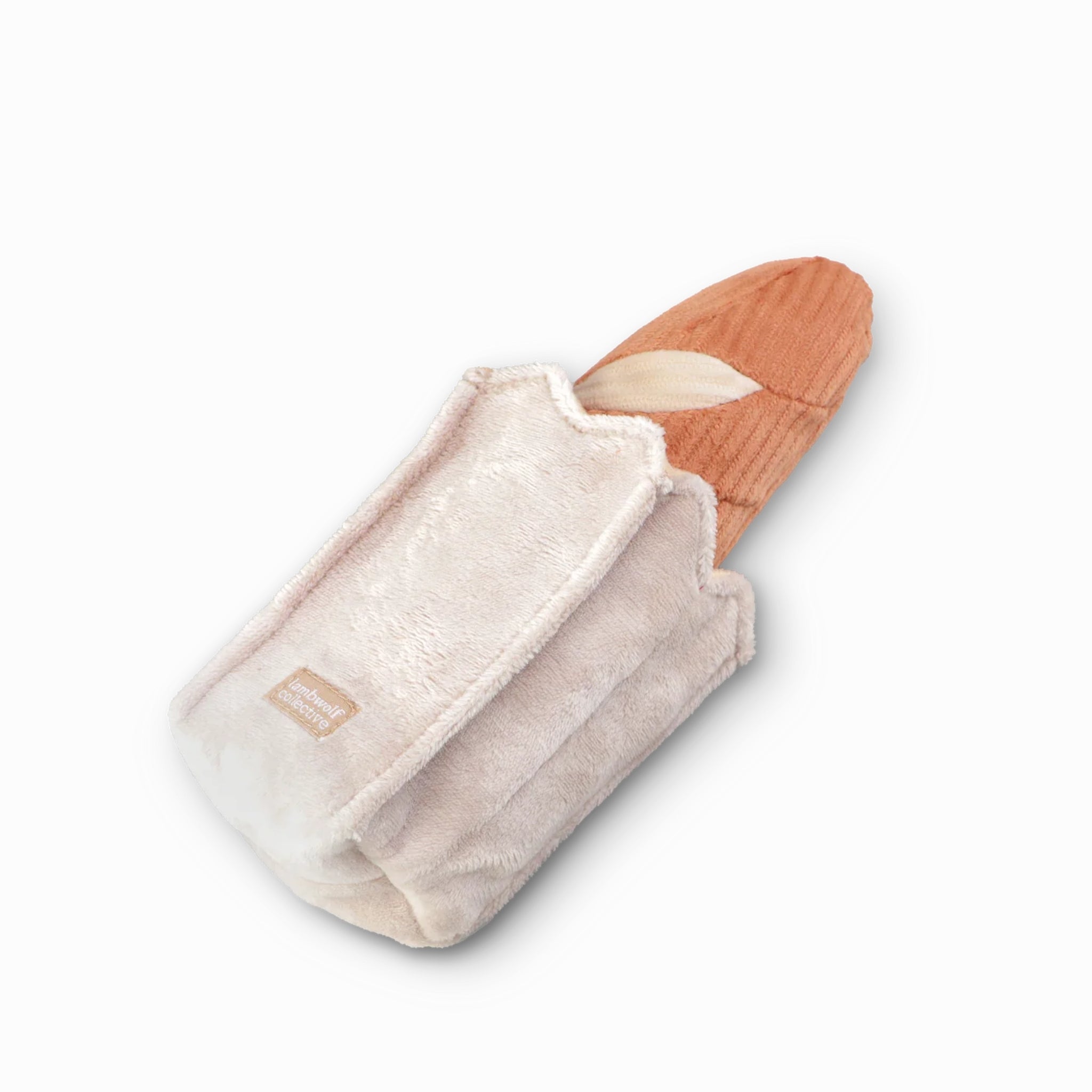 Studio product shot of the Lambwolf Collective Mini Baguette interactive dog toy, featuring a tan corduroy plush bread loaf tucked inside a beige velvet paper-style bag pouch.