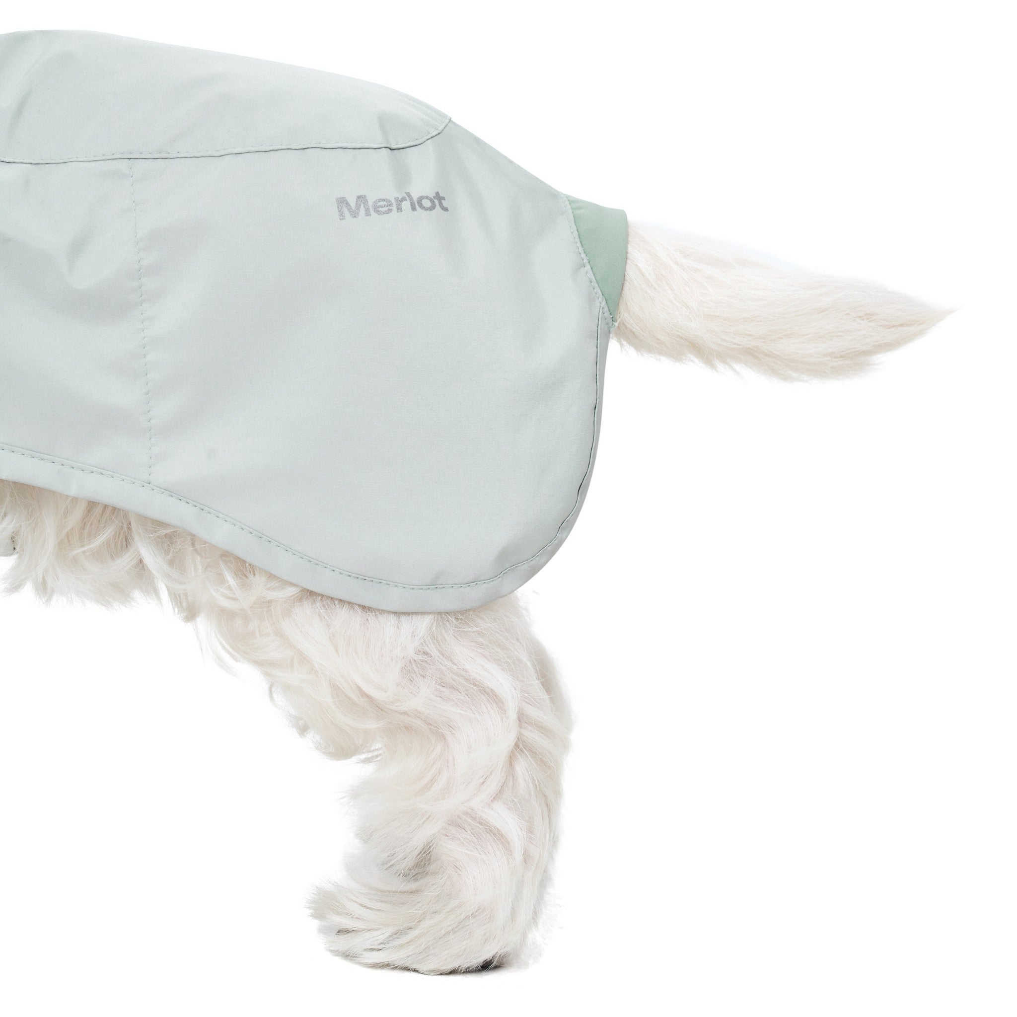 A close-up detail shot focusing on the rear hip section of the lime stone Merlot Ain™ raincoat, showcasing the clean curved hem, tail opening, and the reflective silver brand name print.