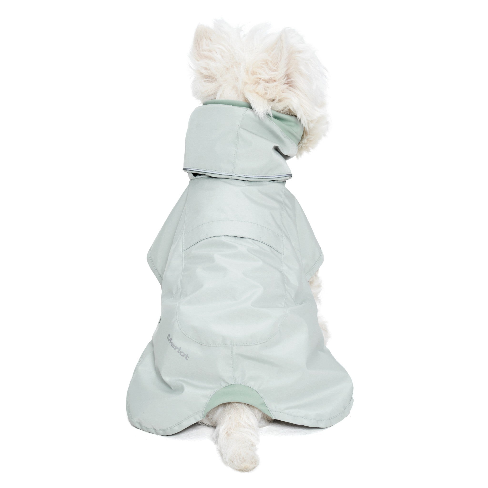 Direct back view of a white dog sitting down facing away from the camera, displaying the clean structural lines, tail clearance, and full dorsal panel coverage of the lime stone green Merlot Ain™ rain suit.