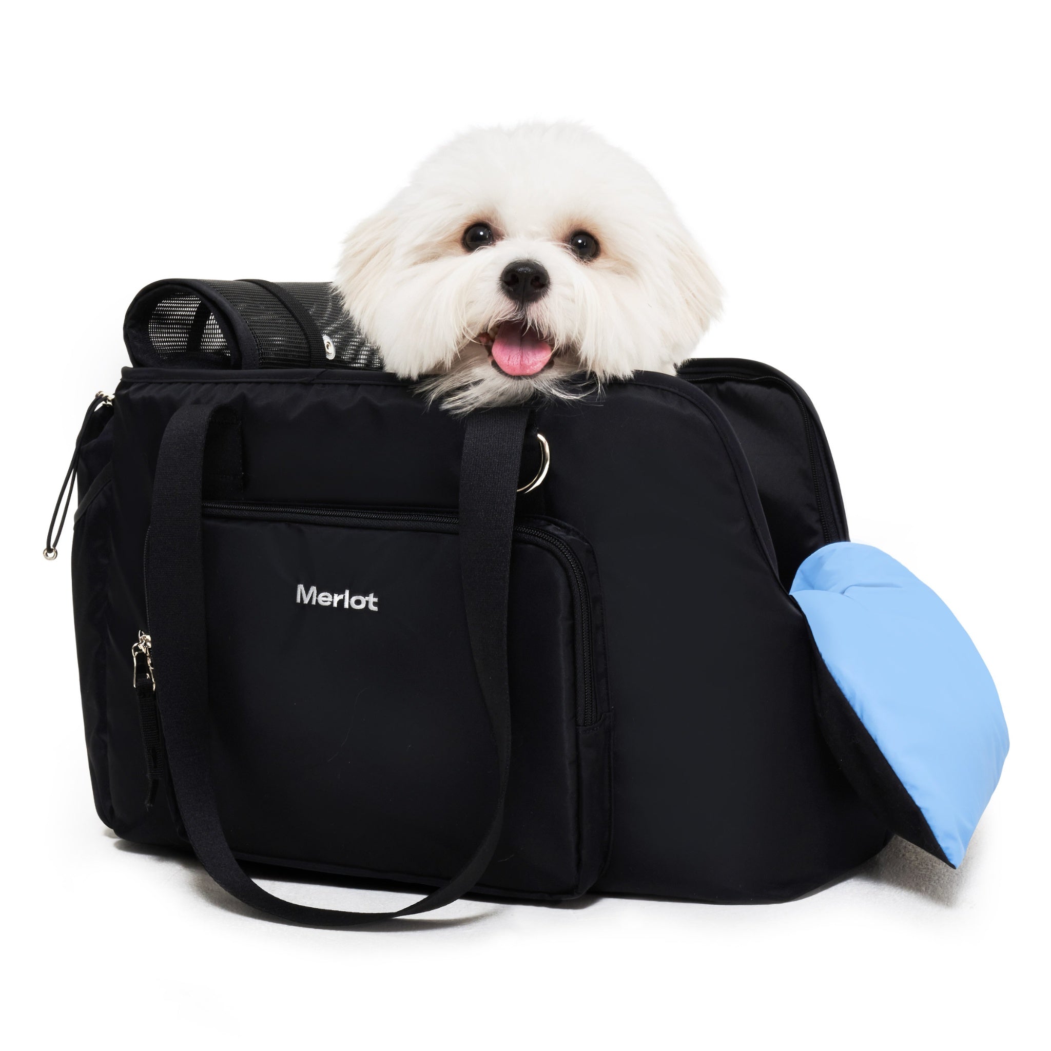Side profile view of a fluffy white small dog looking out from the black Merlot Mermer pet travel tote bag, featuring a light blue padded cushion draped over the side opening for extra chin comfort.