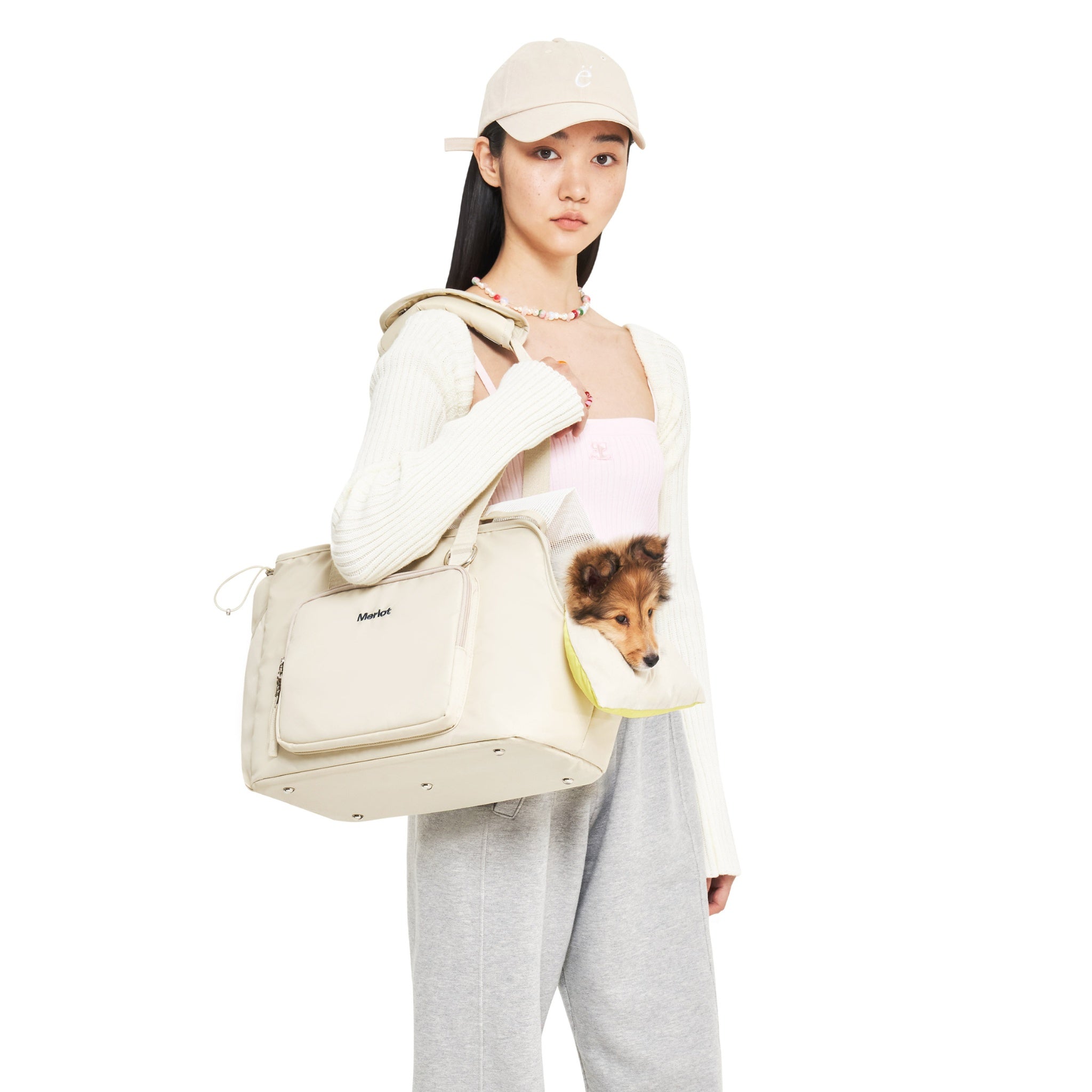 A fashion model wearing the lemon cream Merlot Mermer pet carrier bag on her shoulder, with a small fluffy brown puppy poking its head out over the bright yellow comfort cushion.