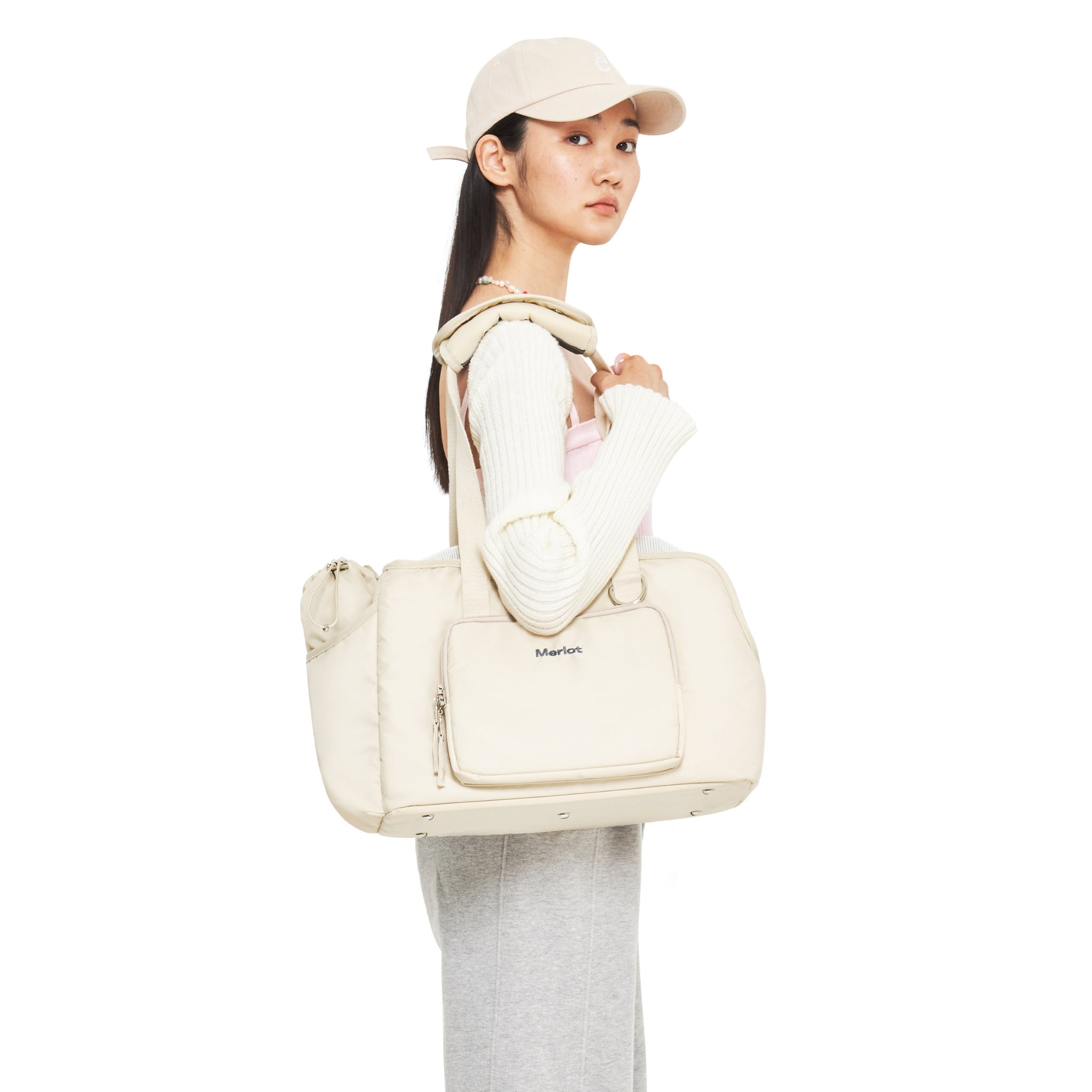 A side profile view of a model carrying the empty lemon cream Merlot Mermer pet travel bag over her shoulder, demonstrating its clean aesthetic and comfortable tote handle drop length.