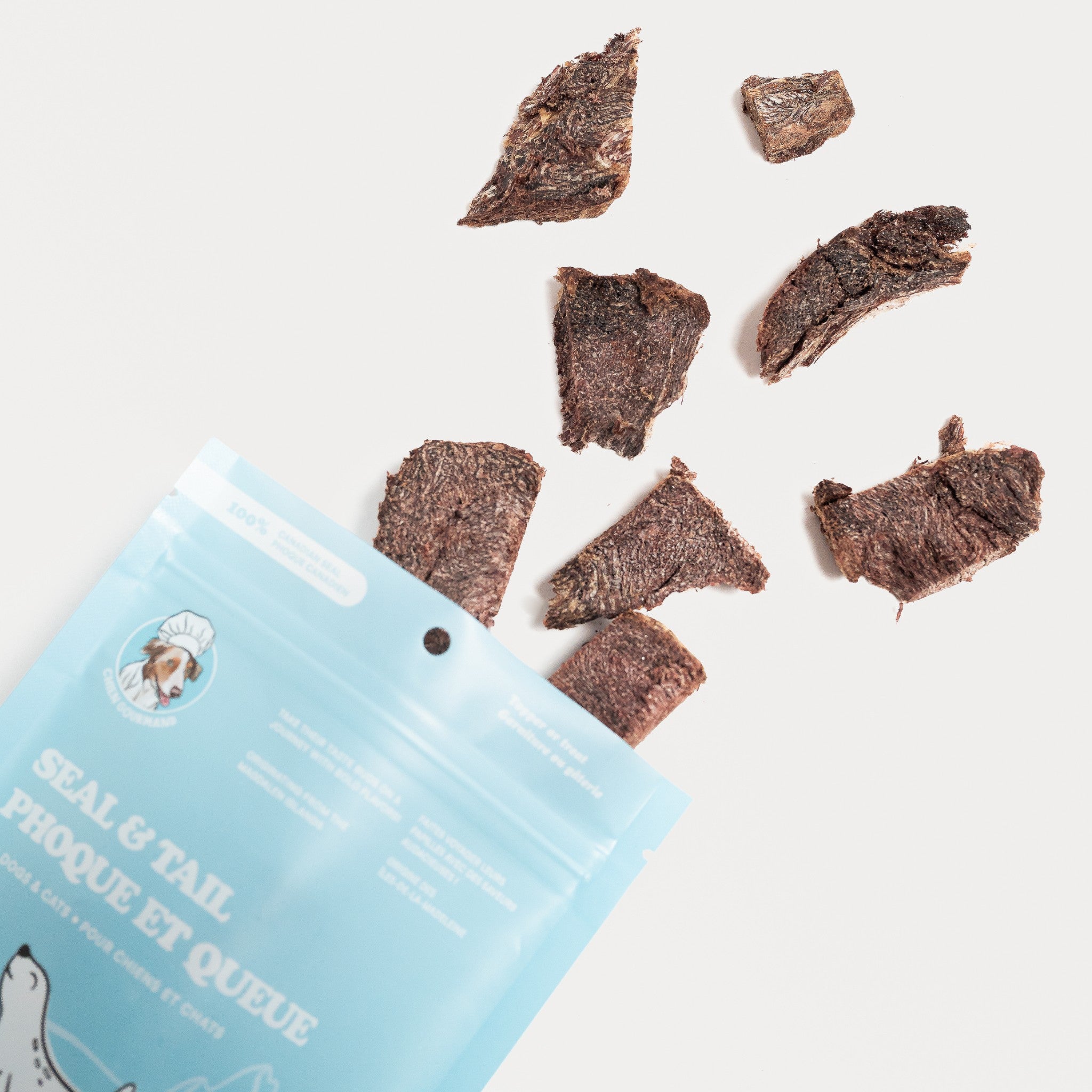 A front-facing studio shot of a 56g light blue stand-up pouch for Chien Gourmand Seal & Tail freeze-dried dog and cat treats, featuring illustrations of seals on ice and bilingual English/French product labeling.