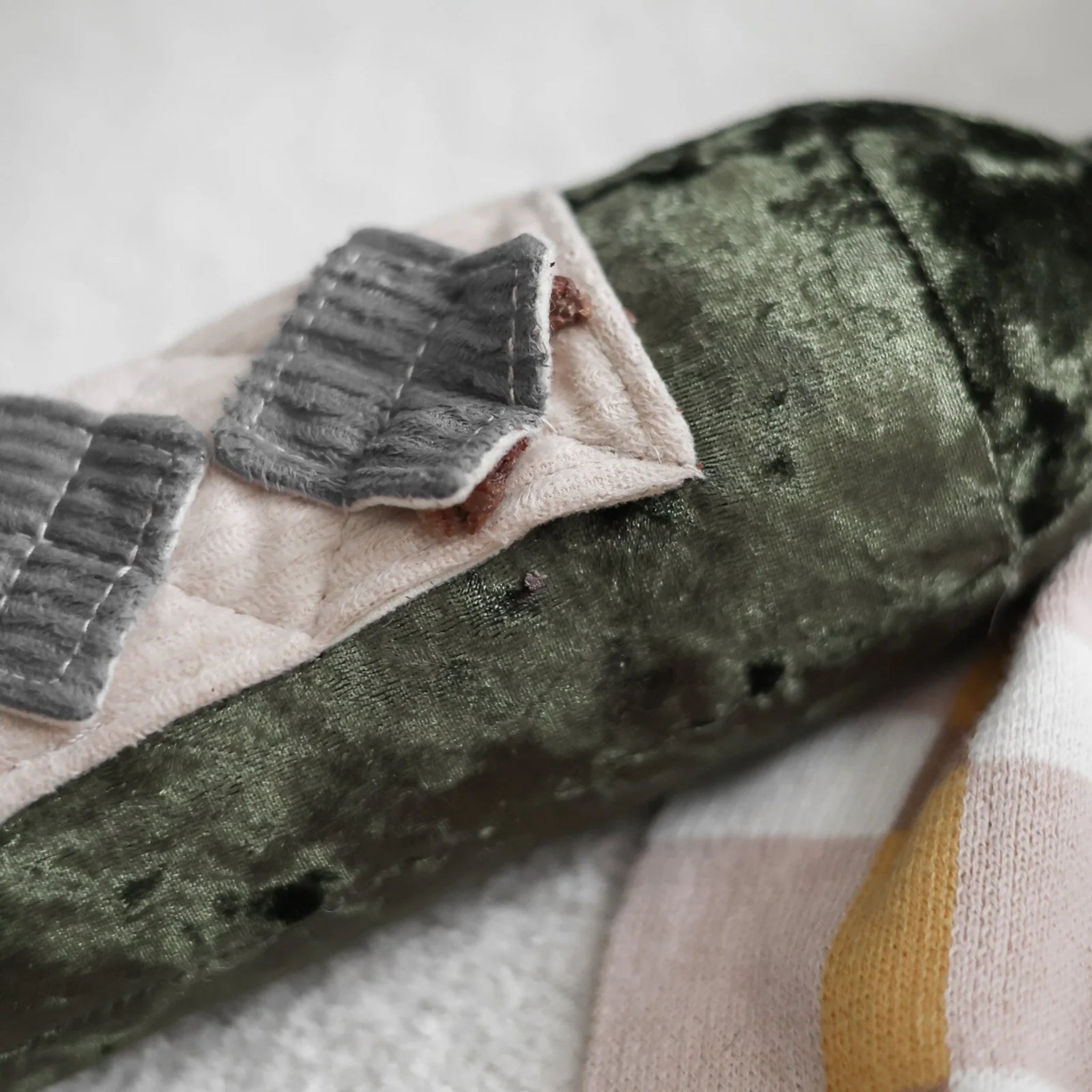 A close-up view of the diamond-shaped corduroy nosework pockets on the plush wine bottle label, showing hidden dry dog training treats tucked inside for foraging enrichment.