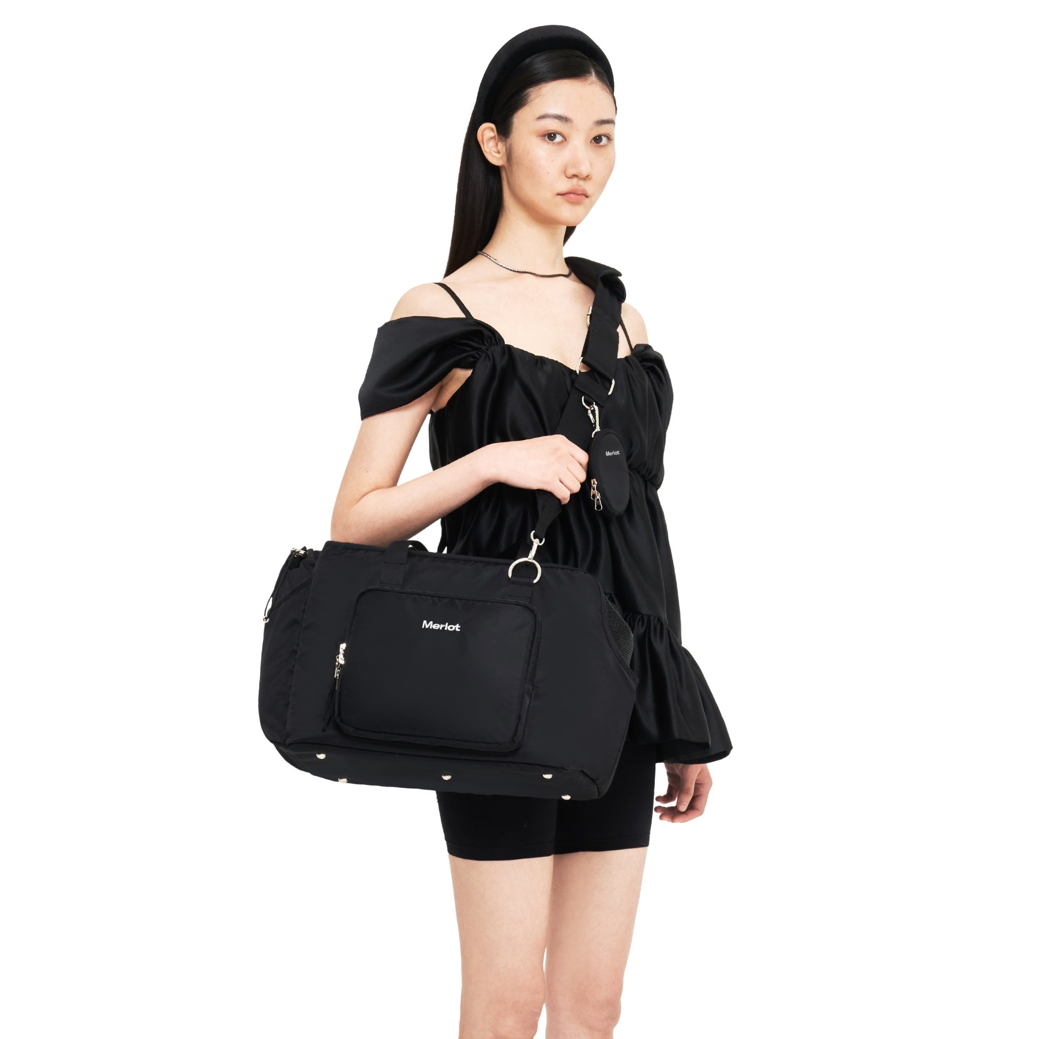 Side view of a model wearing the black Merlot Mermer dog carrier bag using the adjustable wide cross-body shoulder strap with the attached mini pouch.