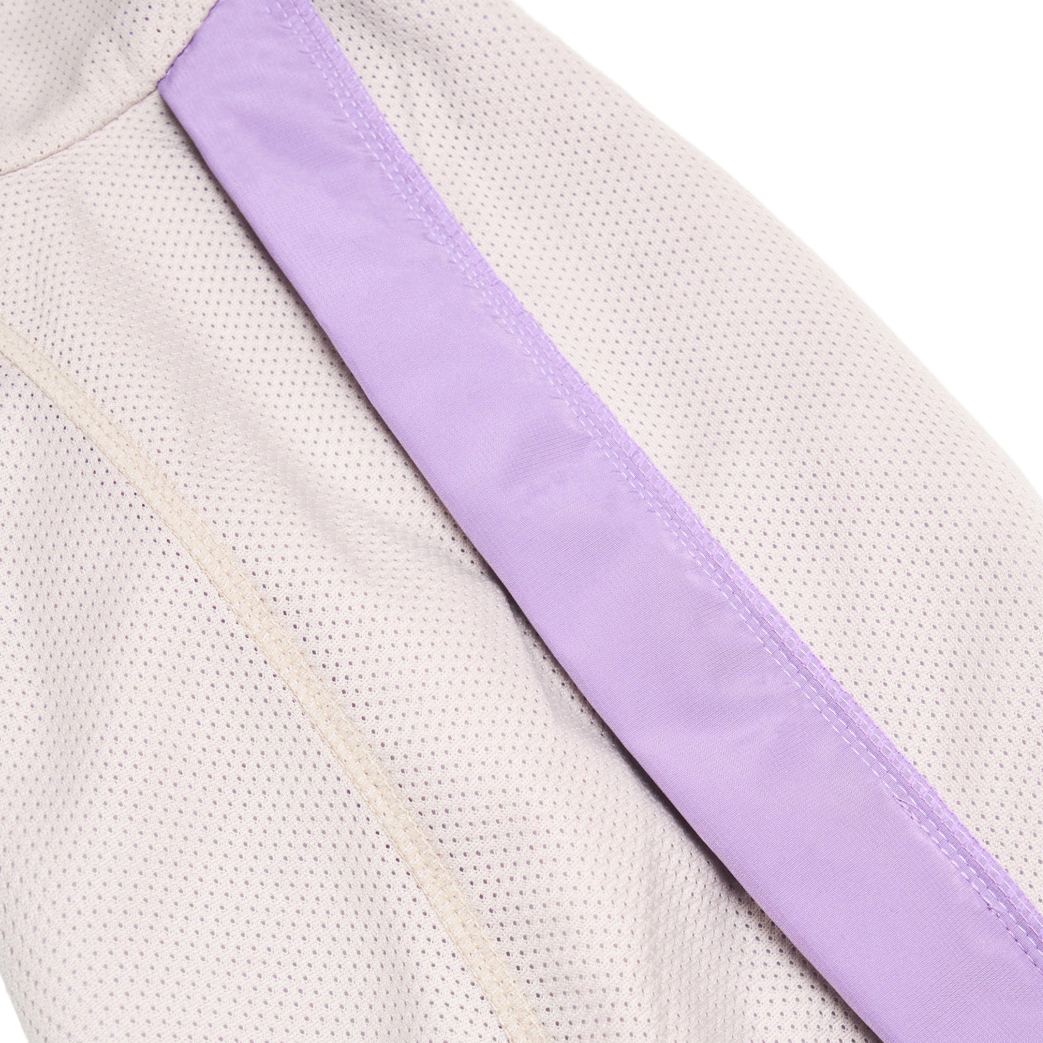 A close-up product detail shot focusing on the lightweight, breathable lavender mesh inner lining and reinforced flatlock stitching of the purple Merlot Shelter dog jacket.