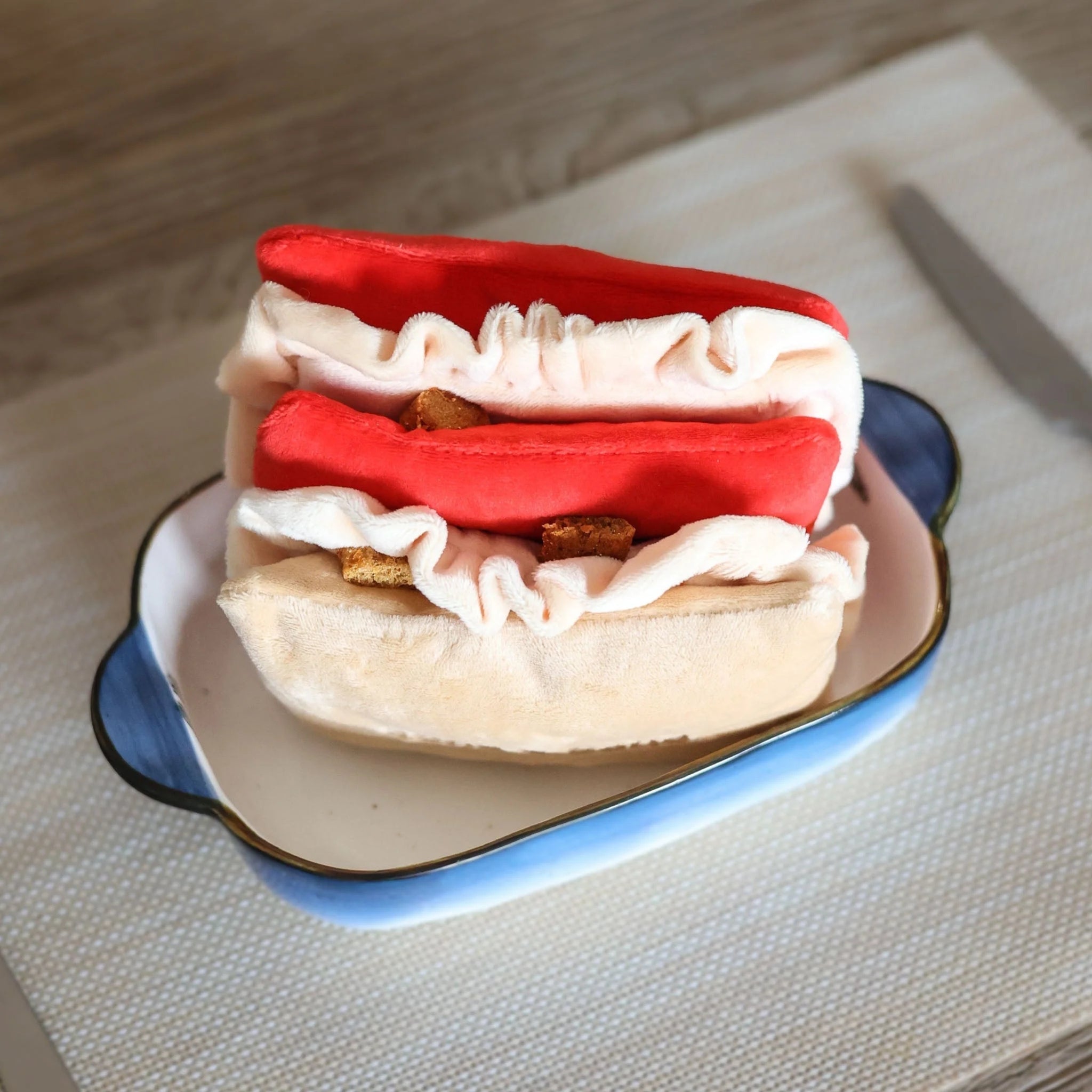 Close-up of the Lasagna plush dog toy split open to show dog treats hidden inside the ruffles for interactive nosework training.