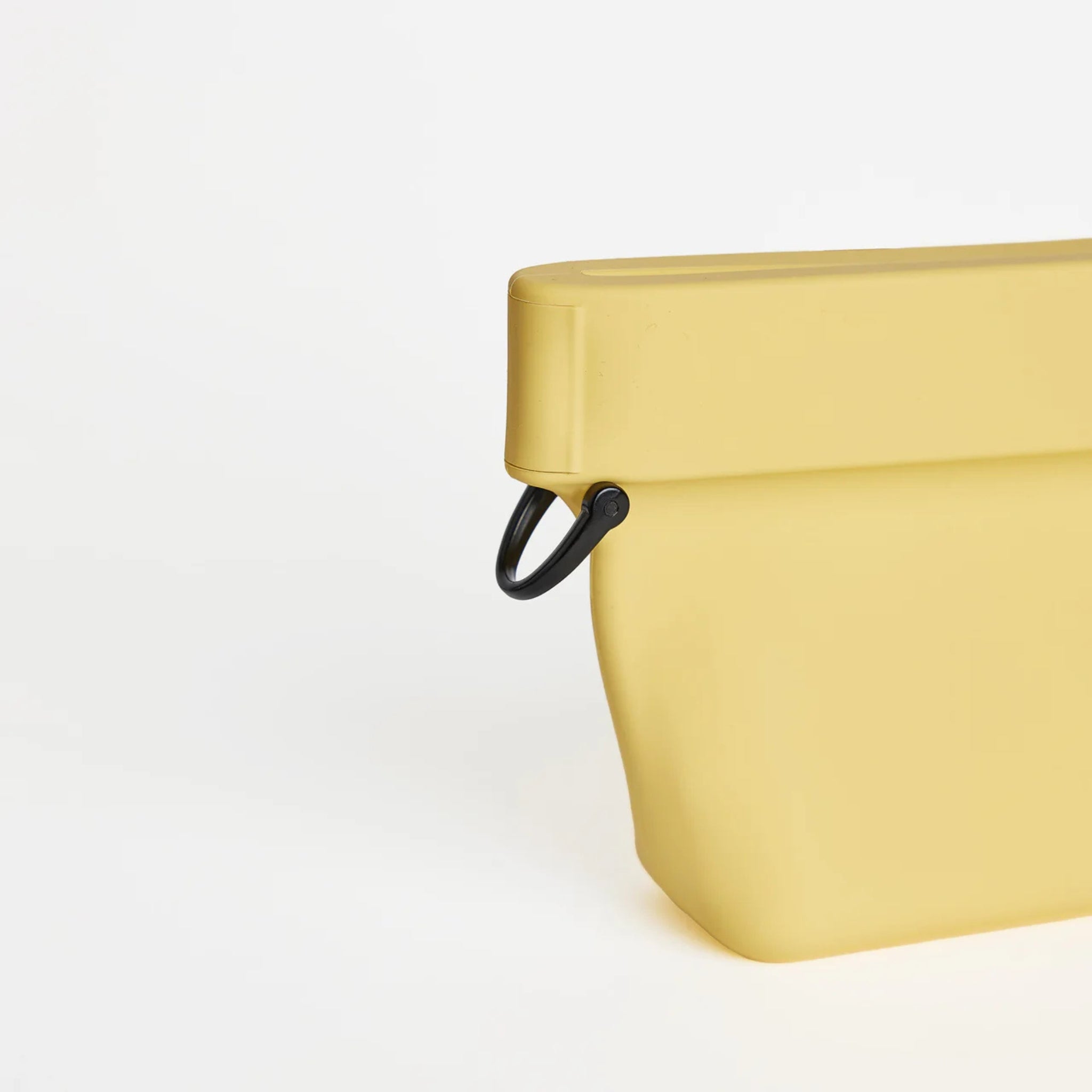 Close-up view of the durable black D-ring attached to the side of the sunflower yellow silicone Ultimate Treat Pouch The Mini by Voilapets.