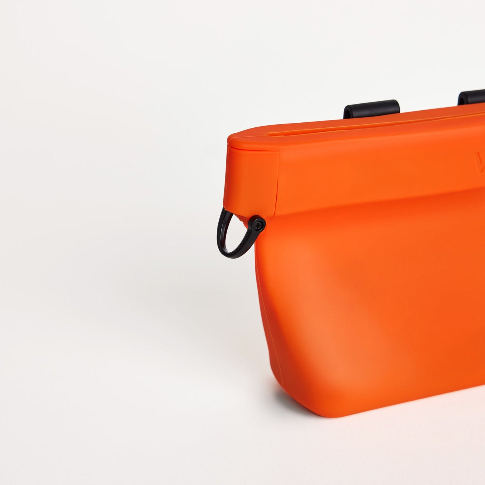 Close-up view of the black metal D-ring attachment clip on the side of the clementine orange silicone Ultimate Treat Pouch The Standard by Voilapets.